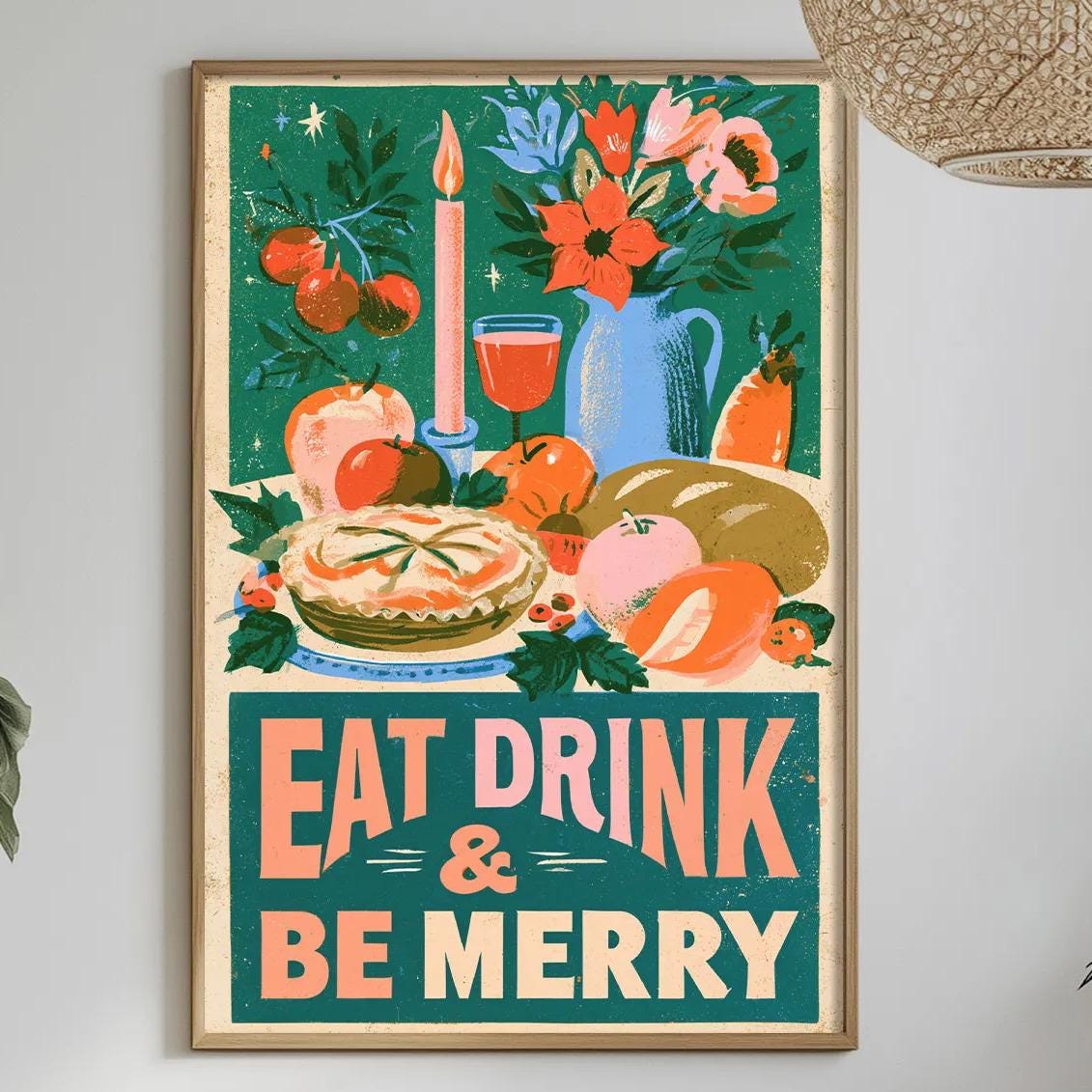 a dining table with a tablecloth, a bowl of fruit, a bottle, and a vase with flowers. Above the table, there is a framed poster with the text "EAT DRINK & BE MERRY" and an illustration of various food items and a candle.