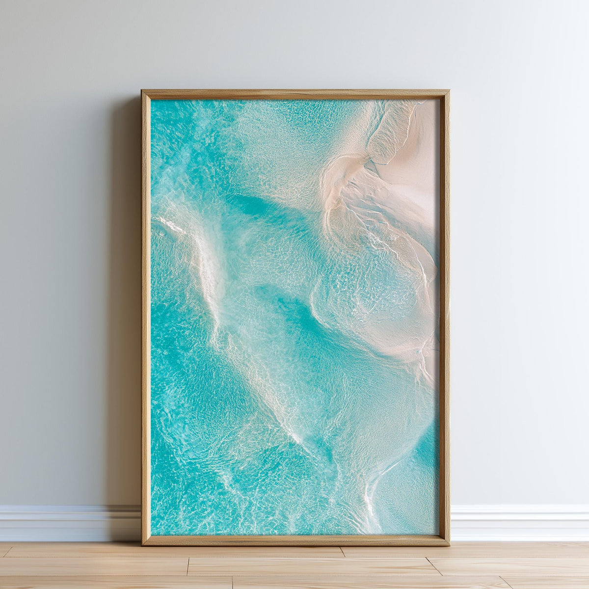 A framed photograph of a serene ocean scene, with turquoise water and white waves, is displayed on a white wall.