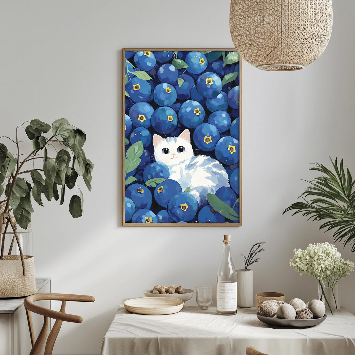 a framed painting of a cat surrounded by blueberries, with a dining table and chairs in the foreground.