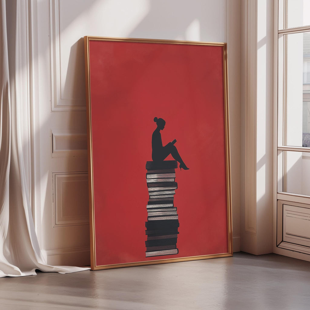 A large framed poster depicting a silhouette of a person sitting on a stack of books, with a red background.