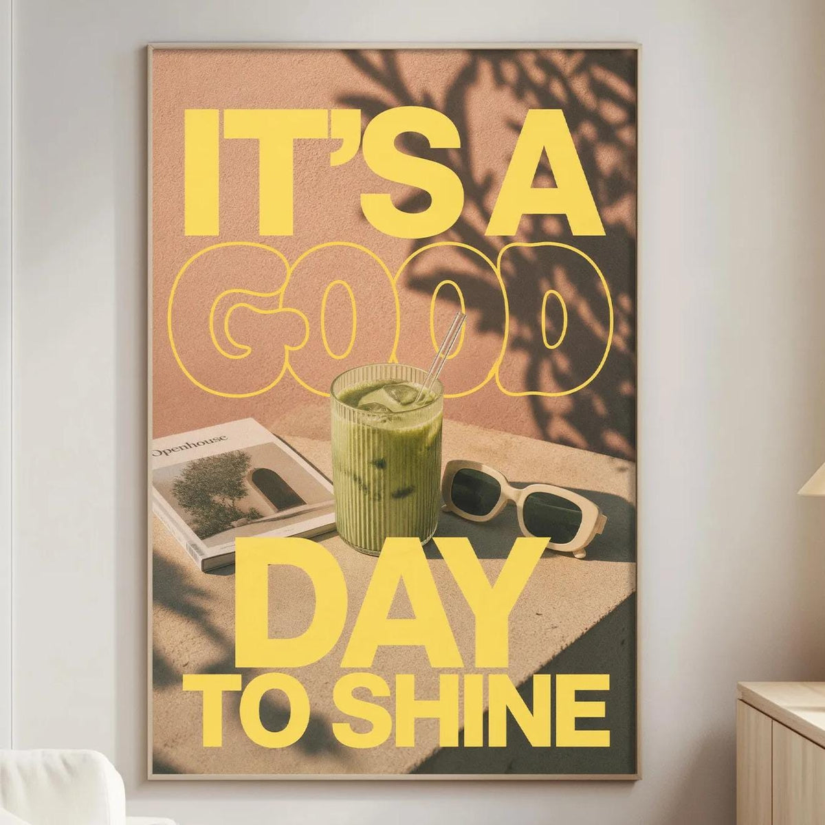 a poster with the text "IT'S A GOOD DAY TO SHINE" displayed on a wall in a living room setting.