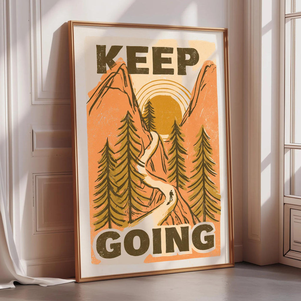 A framed poster with the text "KEEP GOING" and an illustration of a winding path through a forest with mountains in the background.