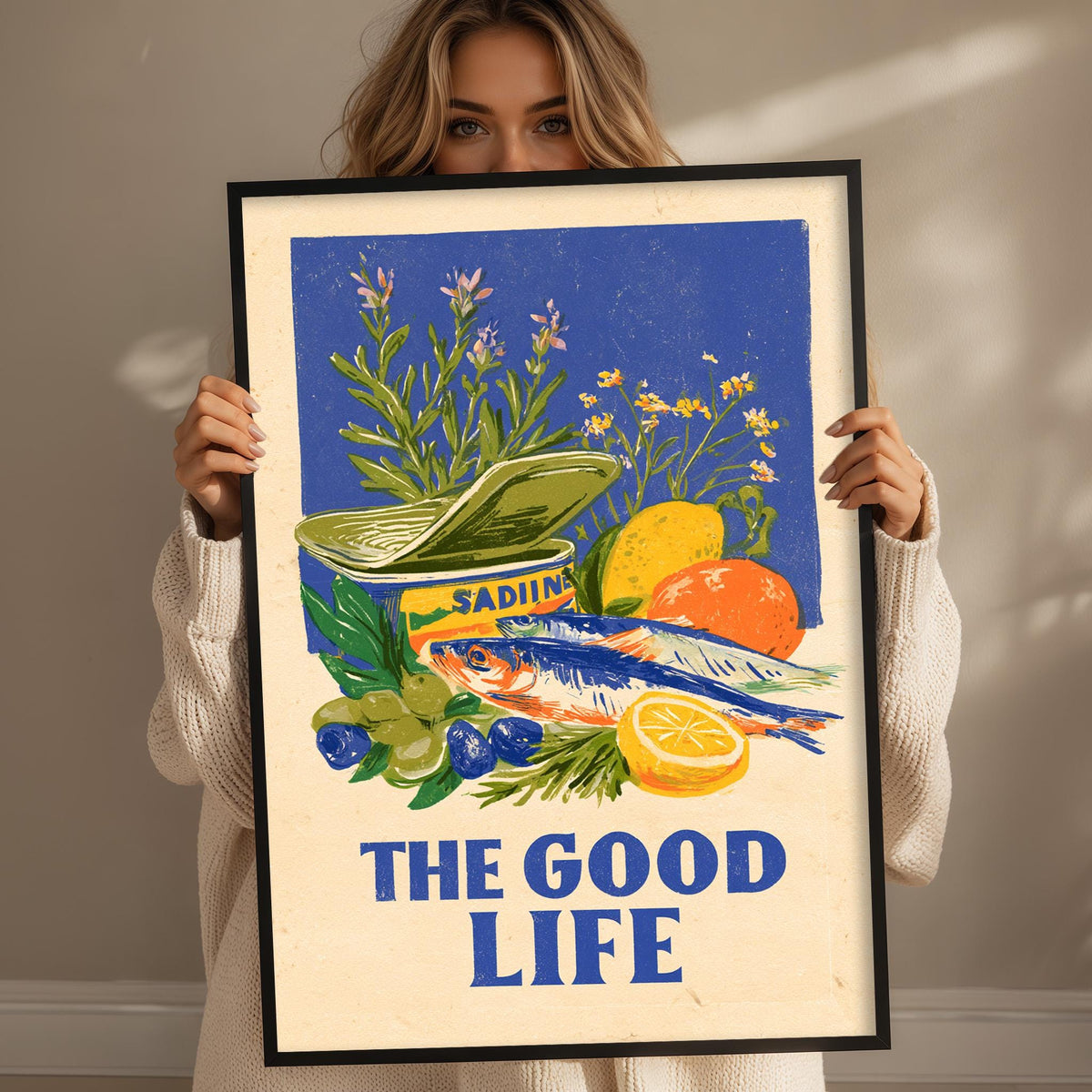 A woman holding a framed poster with an illustration of various fruits and vegetables, including a lemon, orange, and a bowl of what appears to be a type of food.