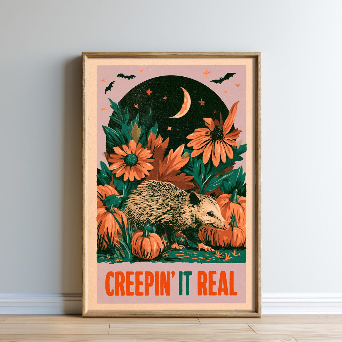 The image is a framed poster with a whimsical and spooky design. It features a hedgehog surrounded by pumpkins and flowers, with a crescent moon and stars in the background. The poster also includes the text "CREEPIN' IT REAL" at the bottom.