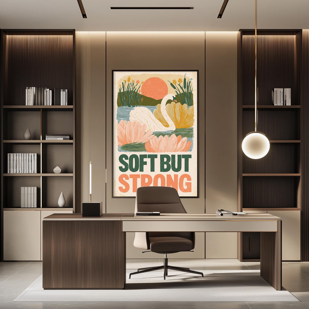 a modern office space with a large framed poster on the wall that says "SOFT BUT STRONG". The office has a wooden desk, a chair, and a bookshelf filled with books. The overall design and decor create a professional and stylish atmosphere.