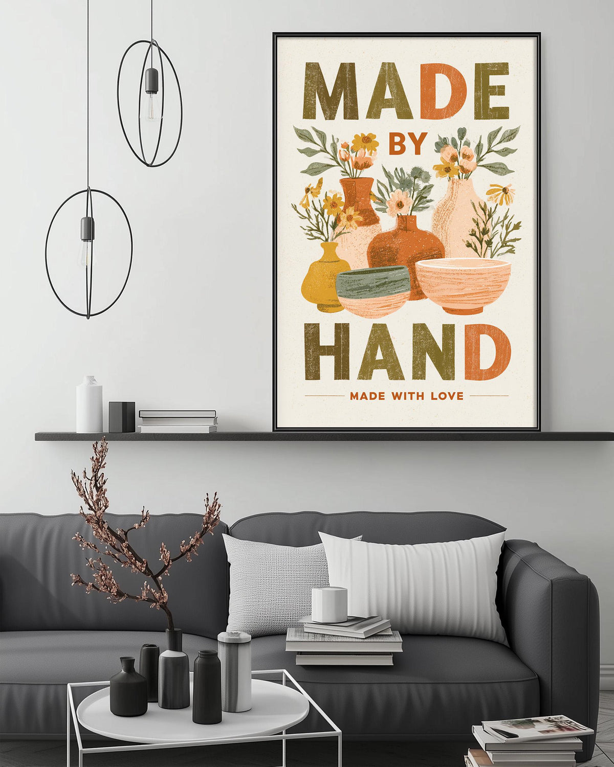 a living room with a gray couch, a coffee table, and a framed poster on the wall. The poster has a floral design and the text "MADE BY HAND MADE WITH LOVE".