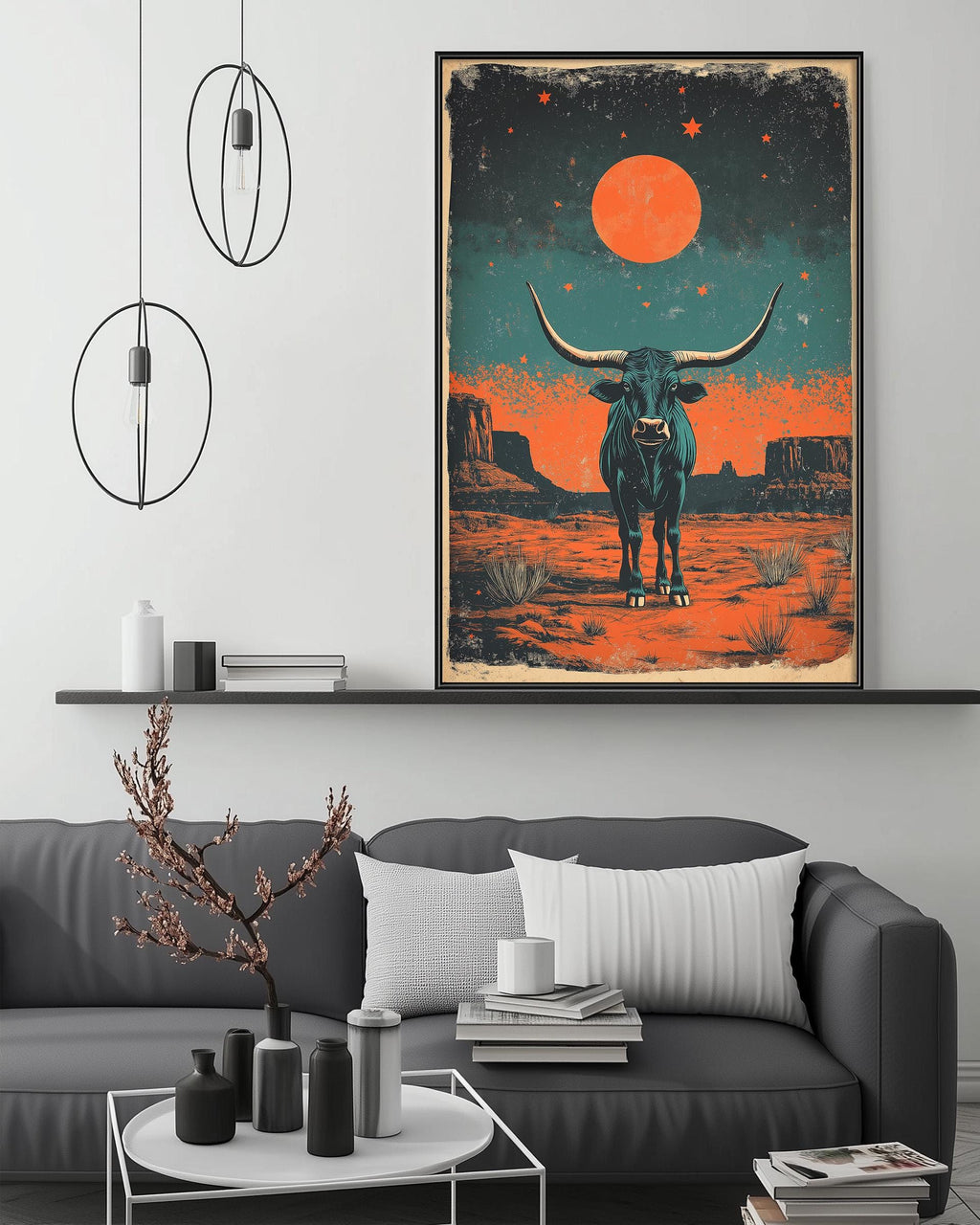 a large framed artwork depicting a bull standing in a desert landscape with a large orange moon in the sky. The artwork is hanging on a wall above a gray couch with a coffee table in front of it.
