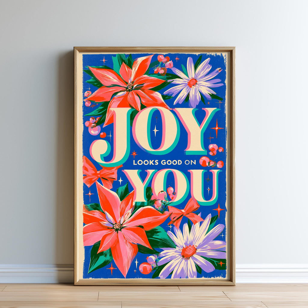 The image is a framed poster with a vibrant floral design and the text "Joy looks good on you".