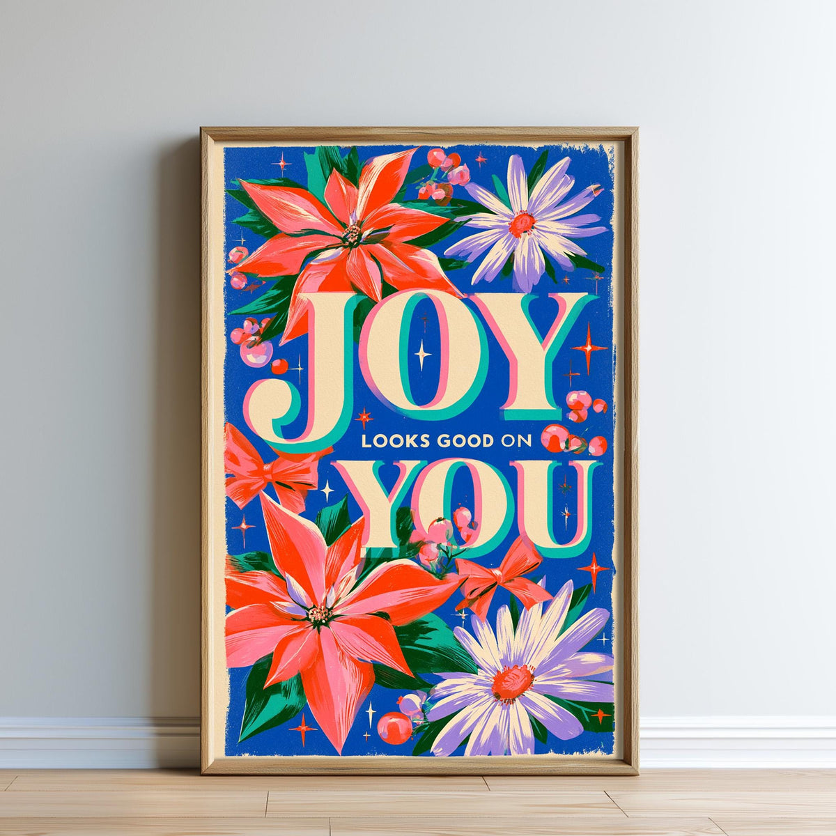 The image is a framed poster with a vibrant floral design and the text "Joy looks good on you".