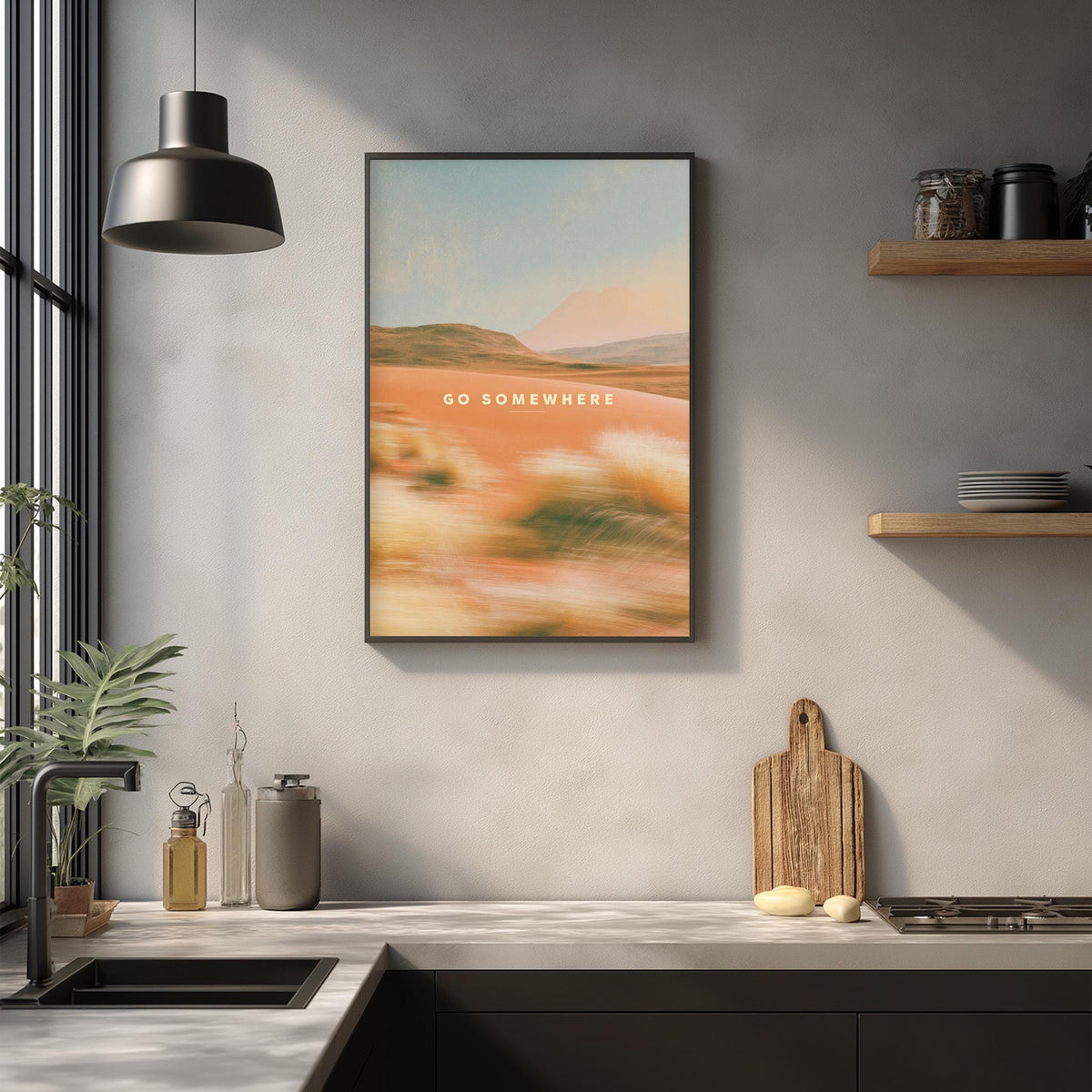 a kitchen counter with various kitchen items, including a cutting board, a sink, and a potted plant. Above the counter, there is a framed picture hanging on the wall with the text "Go somewhere" written on it.