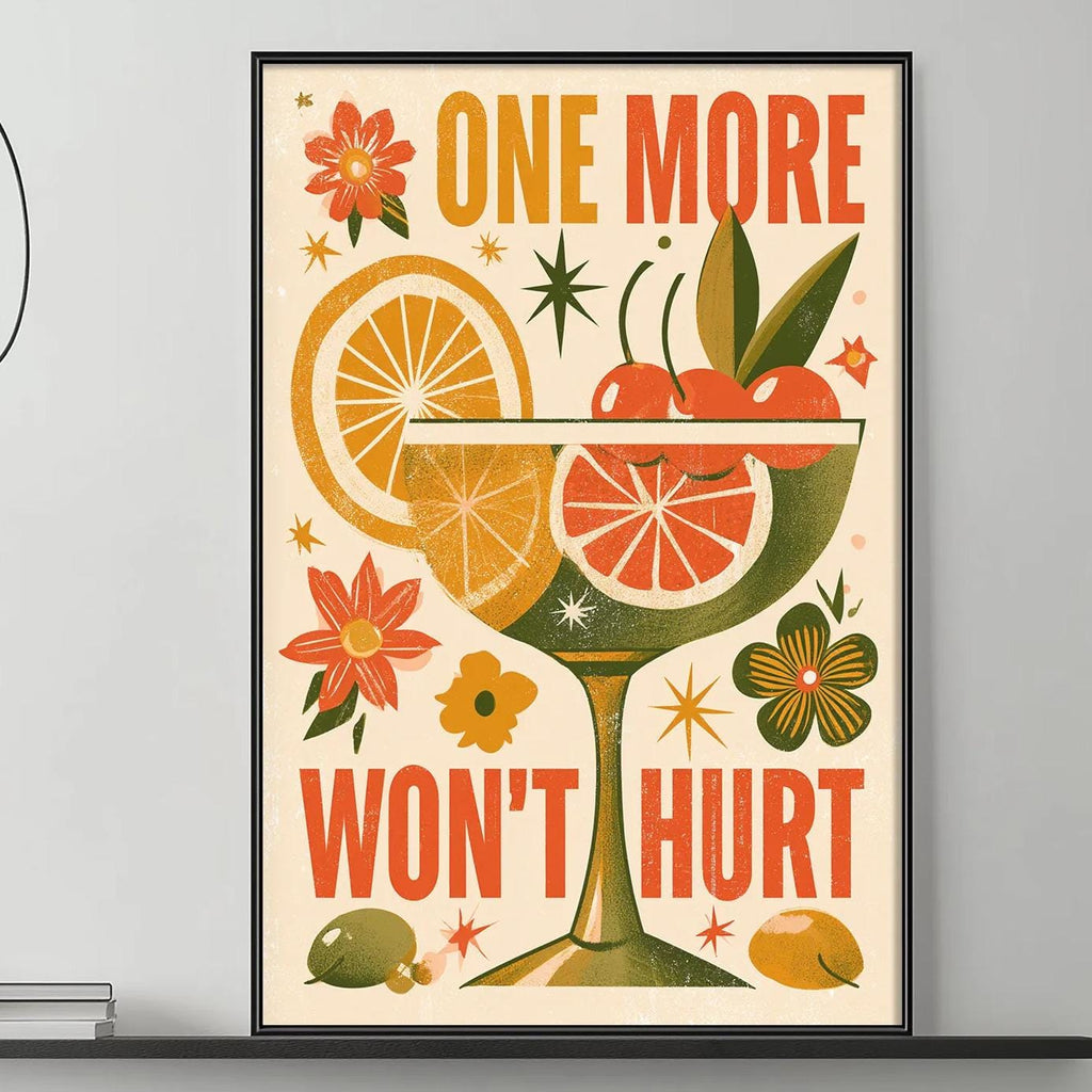 a framed poster with a vibrant design of a cocktail glass, citrus fruits, flowers, and the text "ONE MORE WON'T HURT" displayed on a wall above a gray couch in a living room setting.