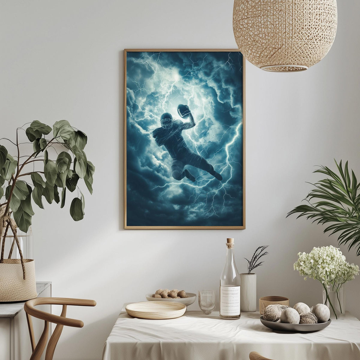 a framed painting of a football player in mid-air, surrounded by a stormy sky and lightning, hanging on a wall above a dining table with various items on it.
