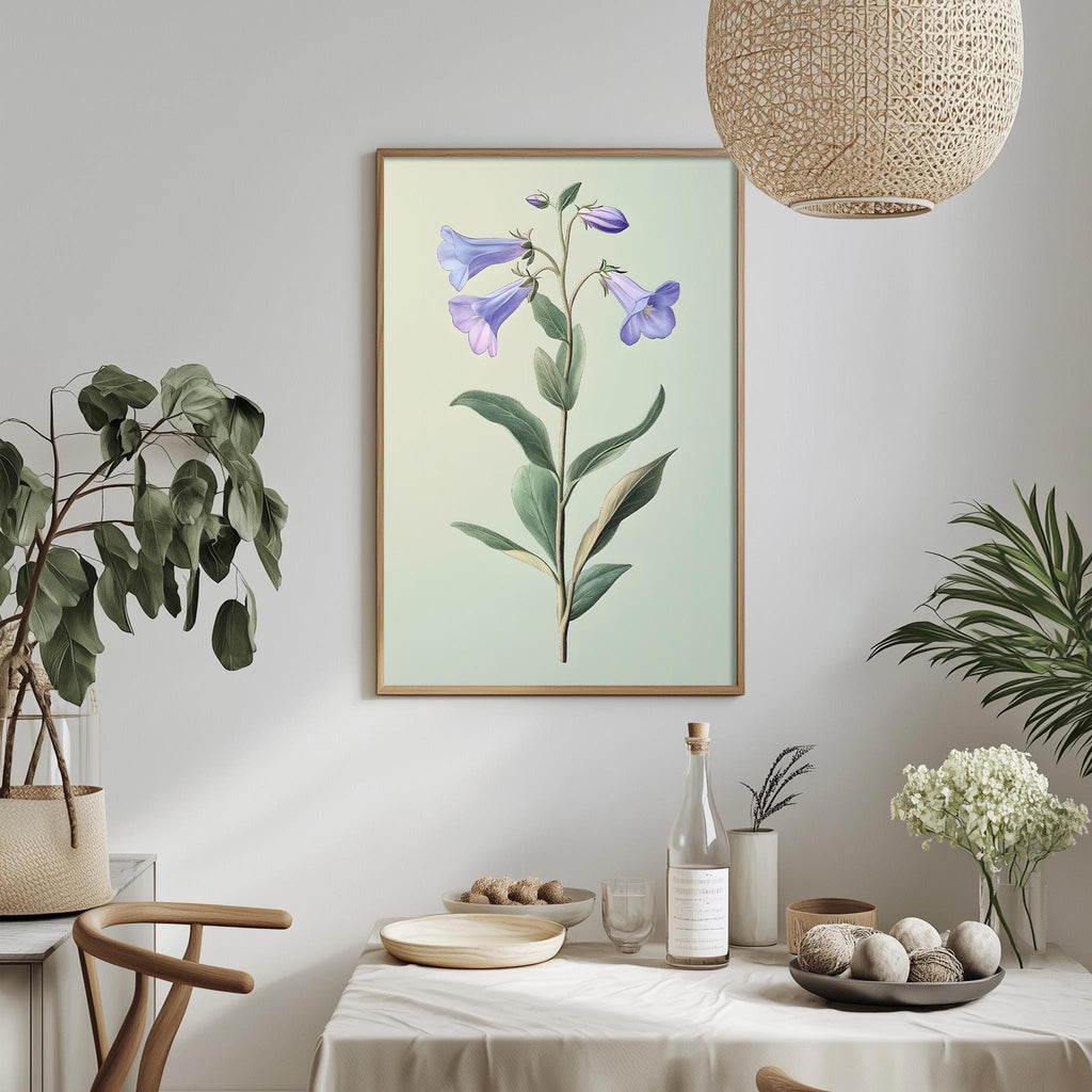 a dining table with a white tablecloth, a bowl of fruit, a bottle, and a vase with flowers. Above the table, there is a framed picture of a plant with purple flowers. The table is set with a bottle, a bowl, and a plate. The room has a minimalist and modern design, with a woven light fixture hanging above the table.