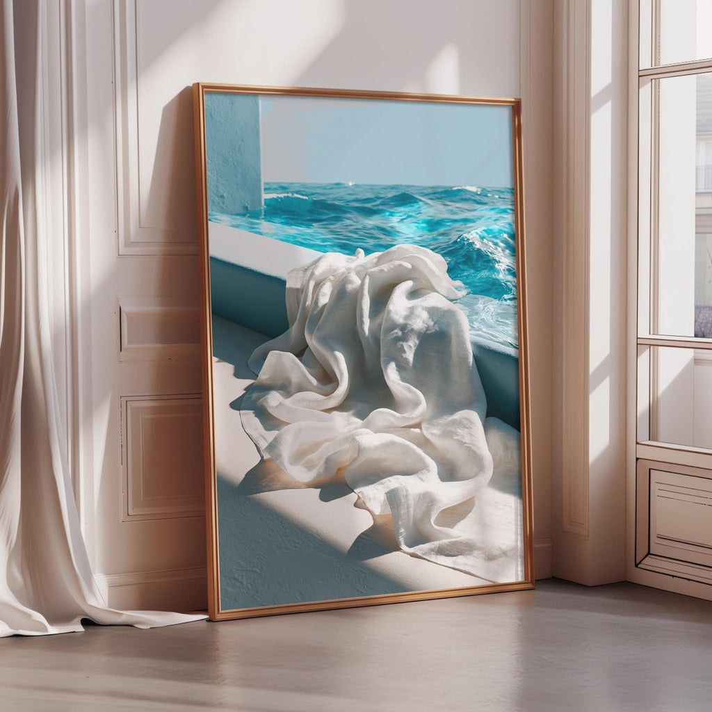 a large framed picture of a white cloth hanging on a wall, with a view of the ocean visible through a window in the background.