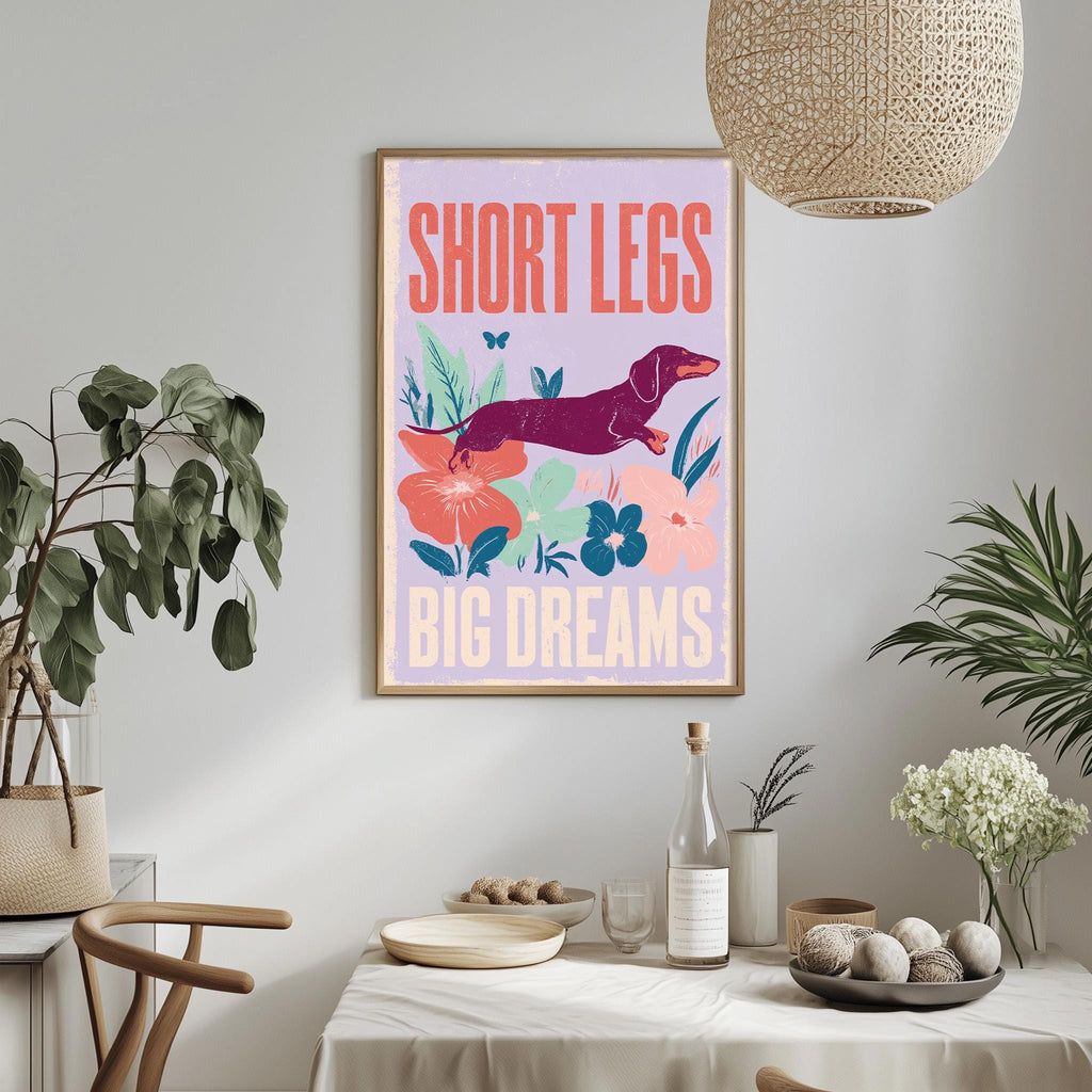 a framed poster with a dog and flowers hanging on a wall above a dining table with various items on it.