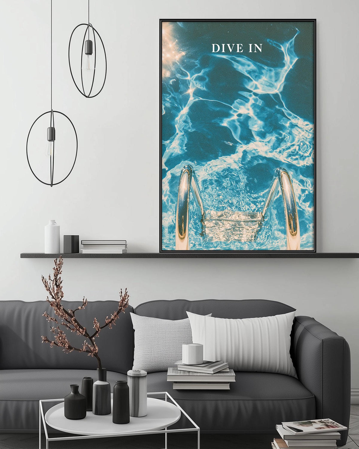 a modern living room with a gray sofa, a coffee table, and a large framed poster of a swimming pool with a diving board. The poster has the text "DIVE IN" written on it.