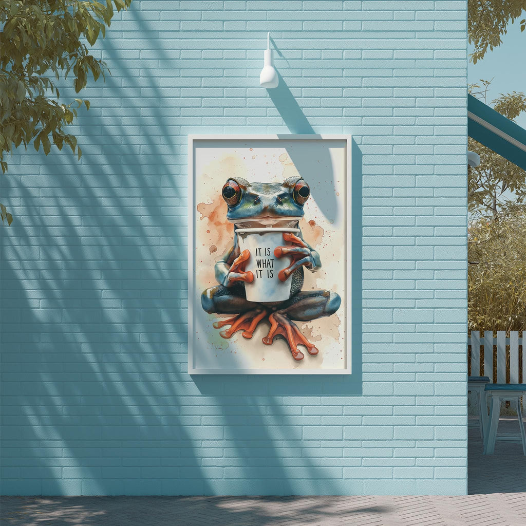 A framed painting of a frog holding a cup with the text "IT IS WHAT IT IS" on it, displayed on a blue brick wall.