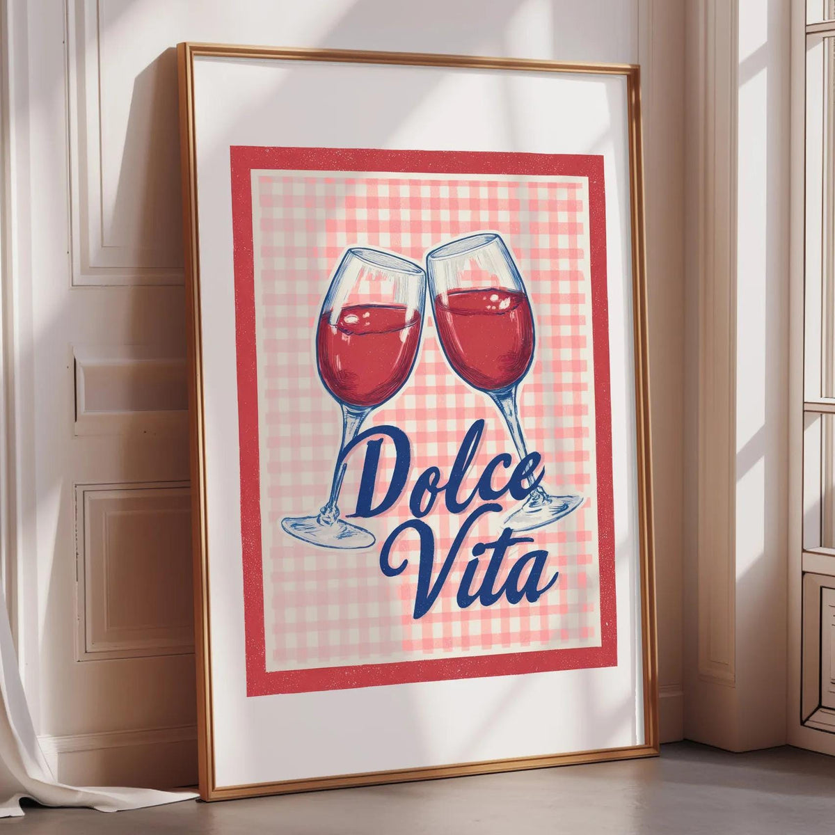 A framed poster with a red and white checkered background and two wine glasses with red wine inside. The text on the poster says "Dolce Vita".