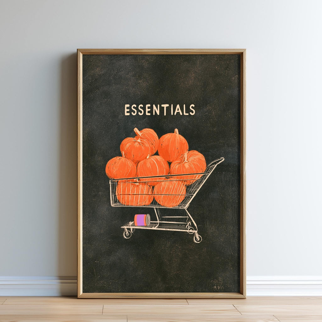 The image is a framed print depicting a shopping cart filled with orange pumpkins, with the word "ESSENTIALS" written above it.