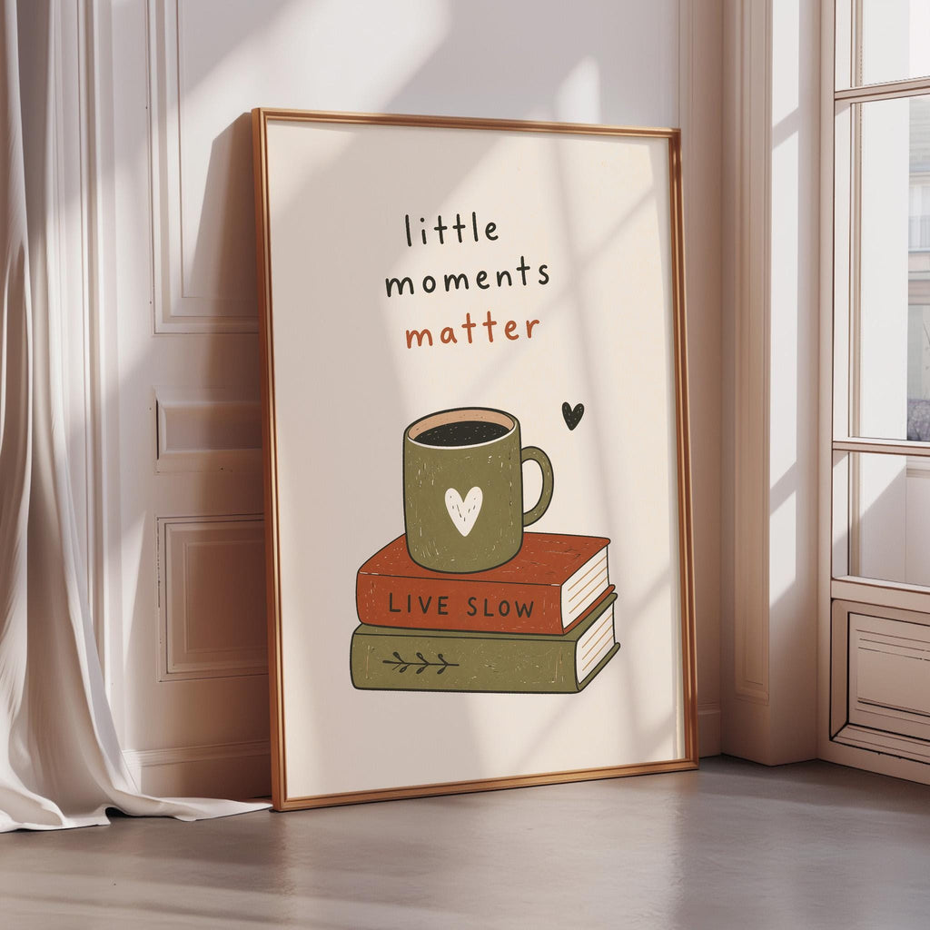 A framed poster with the text "little moments matter" and an illustration of a cup of coffee on top of a stack of books.