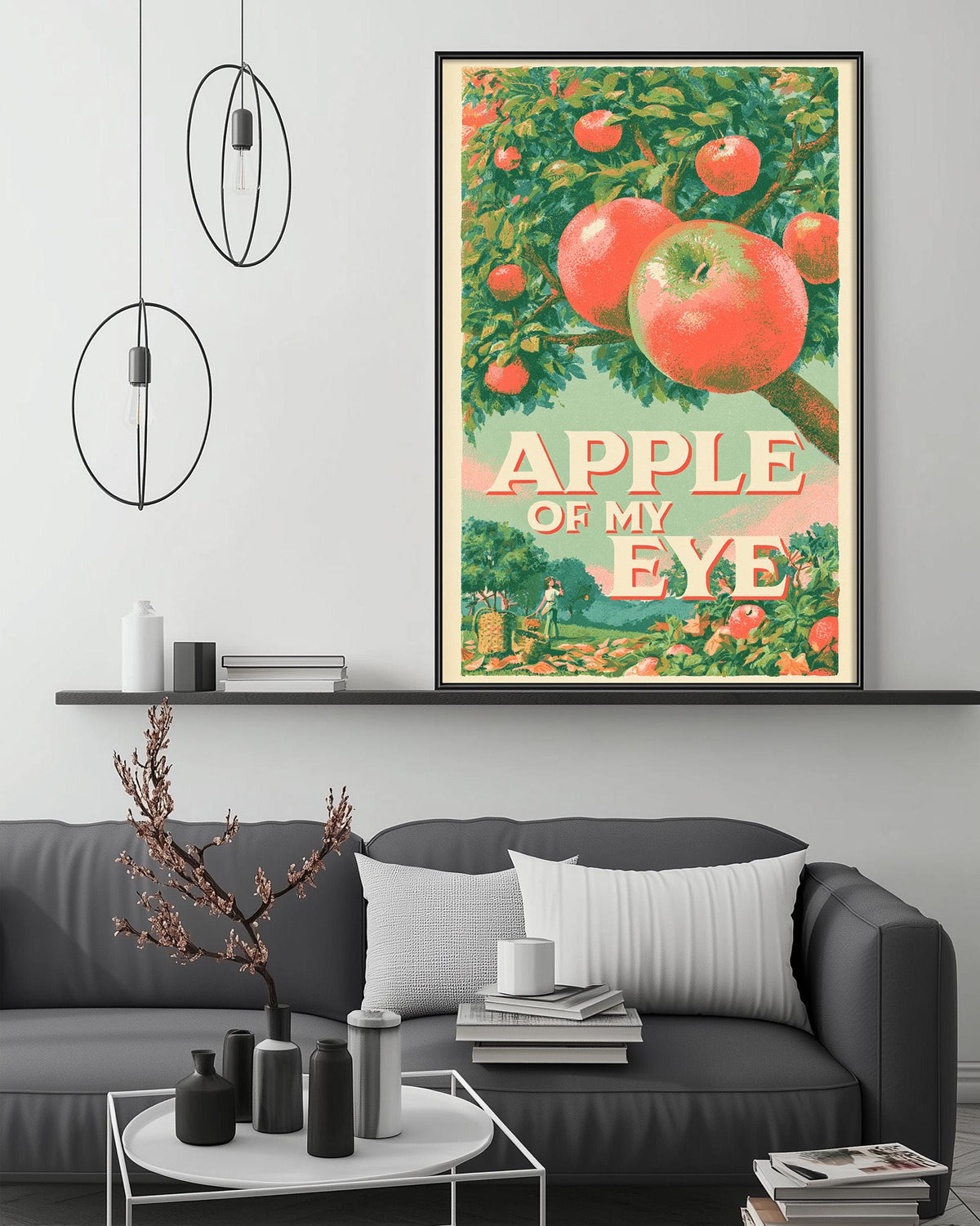 a large framed poster of an apple tree with the text "APPLE OF MY EYE" on it, hanging on a wall above a gray couch with a coffee table in front of it.