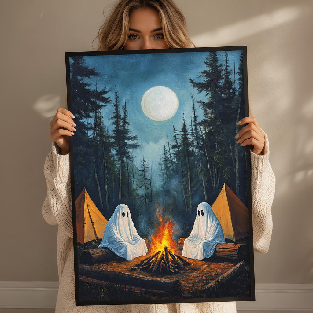 A woman holds up a framed painting depicting two ghostly figures sitting by a campfire in a forest at night, with a full moon in the background.