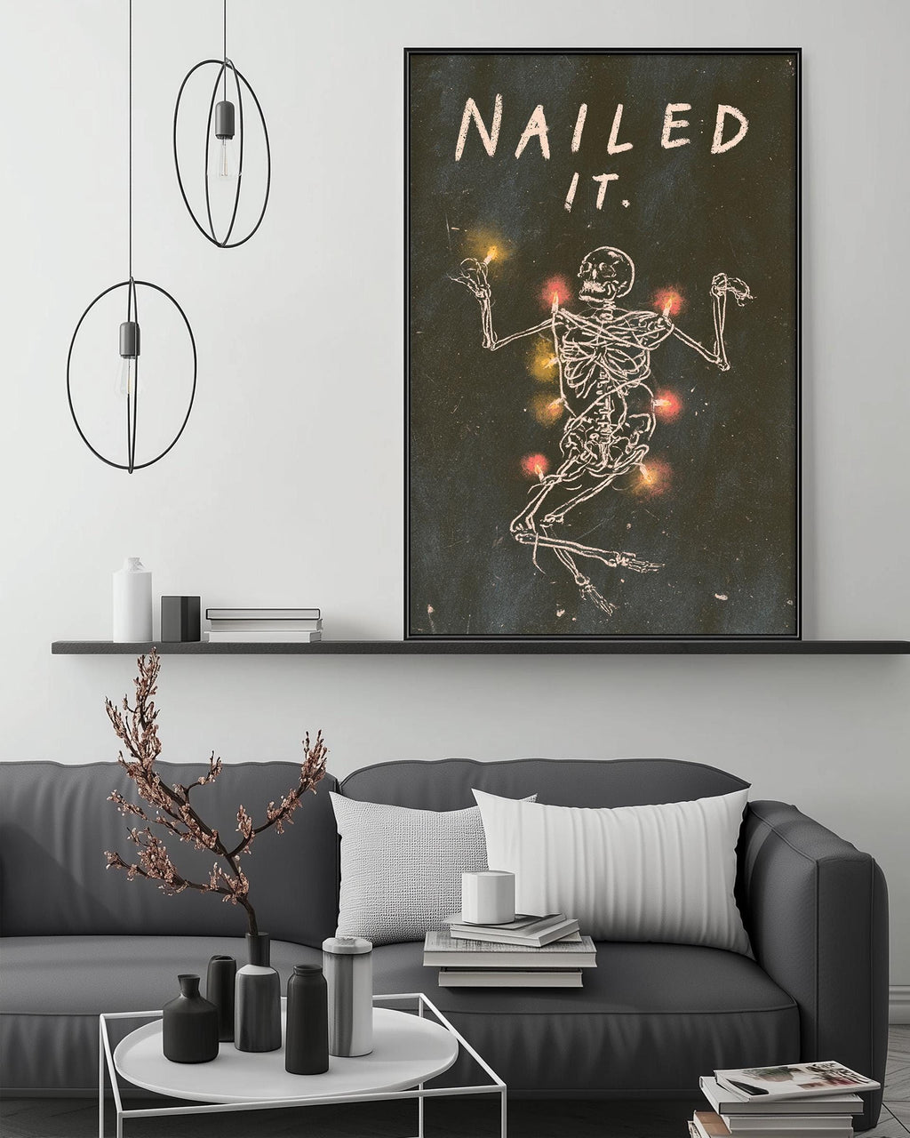 a living room with a gray sofa, a coffee table, and a large framed poster of a skeleton with the text "Nailed it" above it.