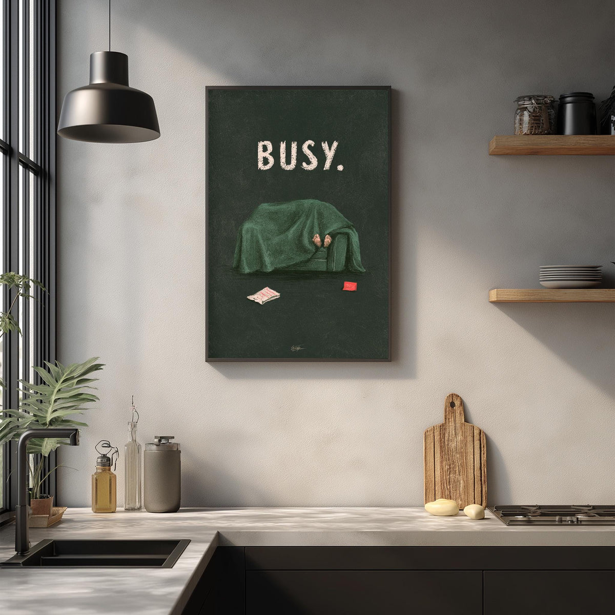 a kitchen counter with various items such as a cutting board, a bottle, and a plant. Above the counter, there is a framed poster with the word "BUSY" written on it.