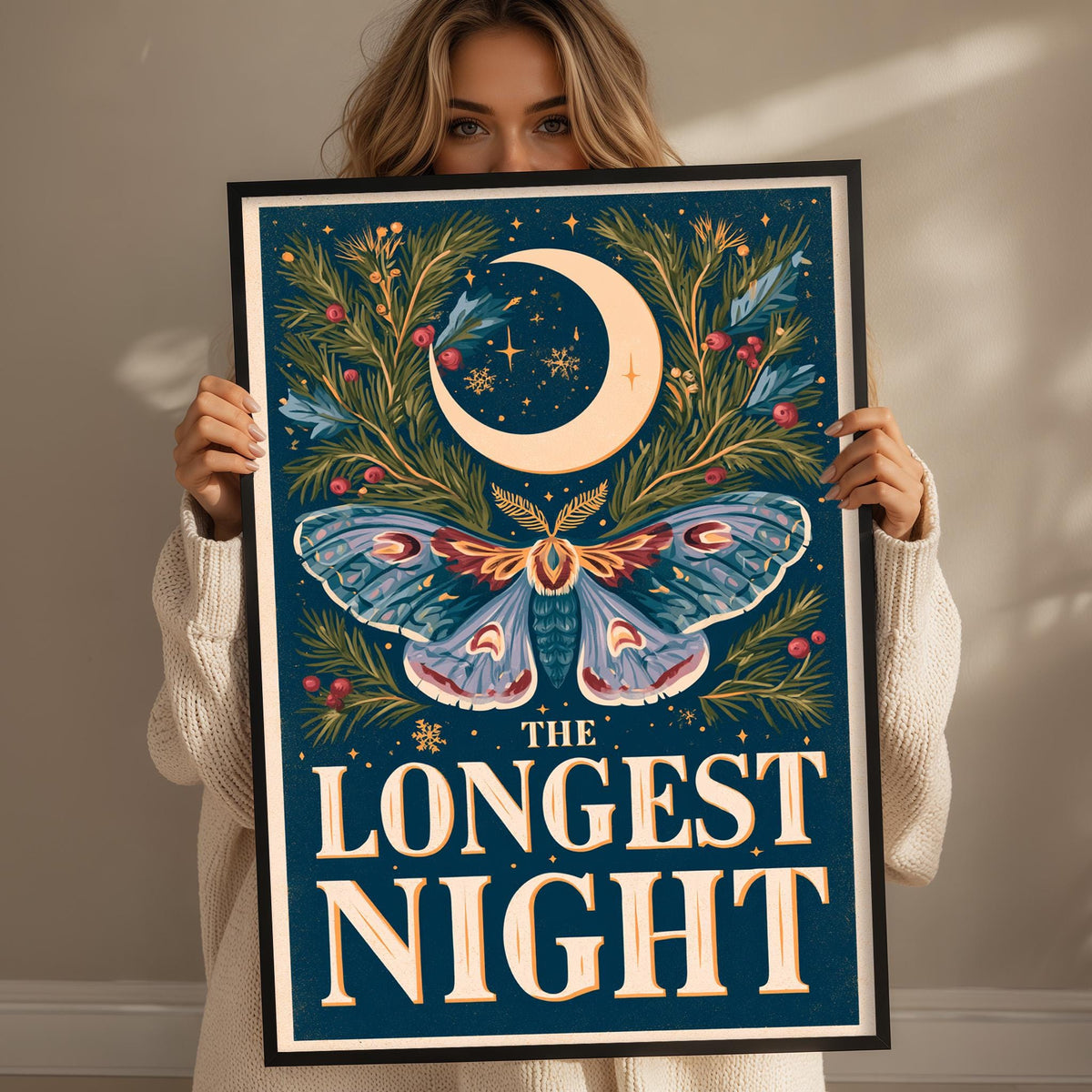 A woman is holding up a framed poster with a large crescent moon and a butterfly design.