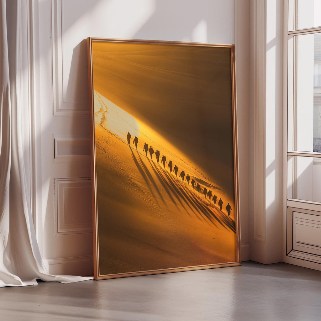 A large framed photograph depicting a group of people walking in a line along a sandy beach, with the sun casting long shadows and creating a warm, golden glow on the scene.