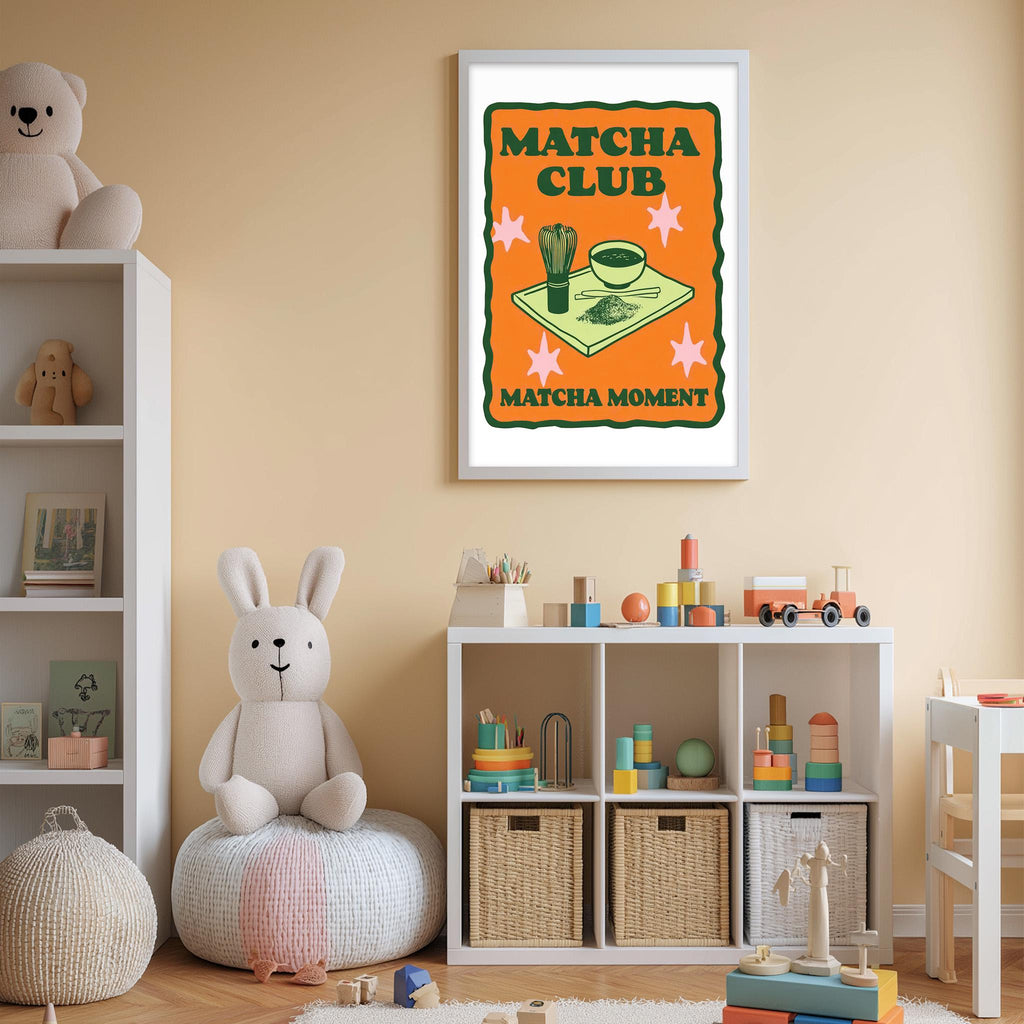 A child's bedroom with a white bookshelf, a stuffed rabbit, and a toy train. Above the bookshelf is a framed poster with the text "MATCHA CLUB MATCHA MOMENT".