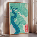 a large framed poster with a stylized tree design in shades of blue and green, placed on a wall near a window.