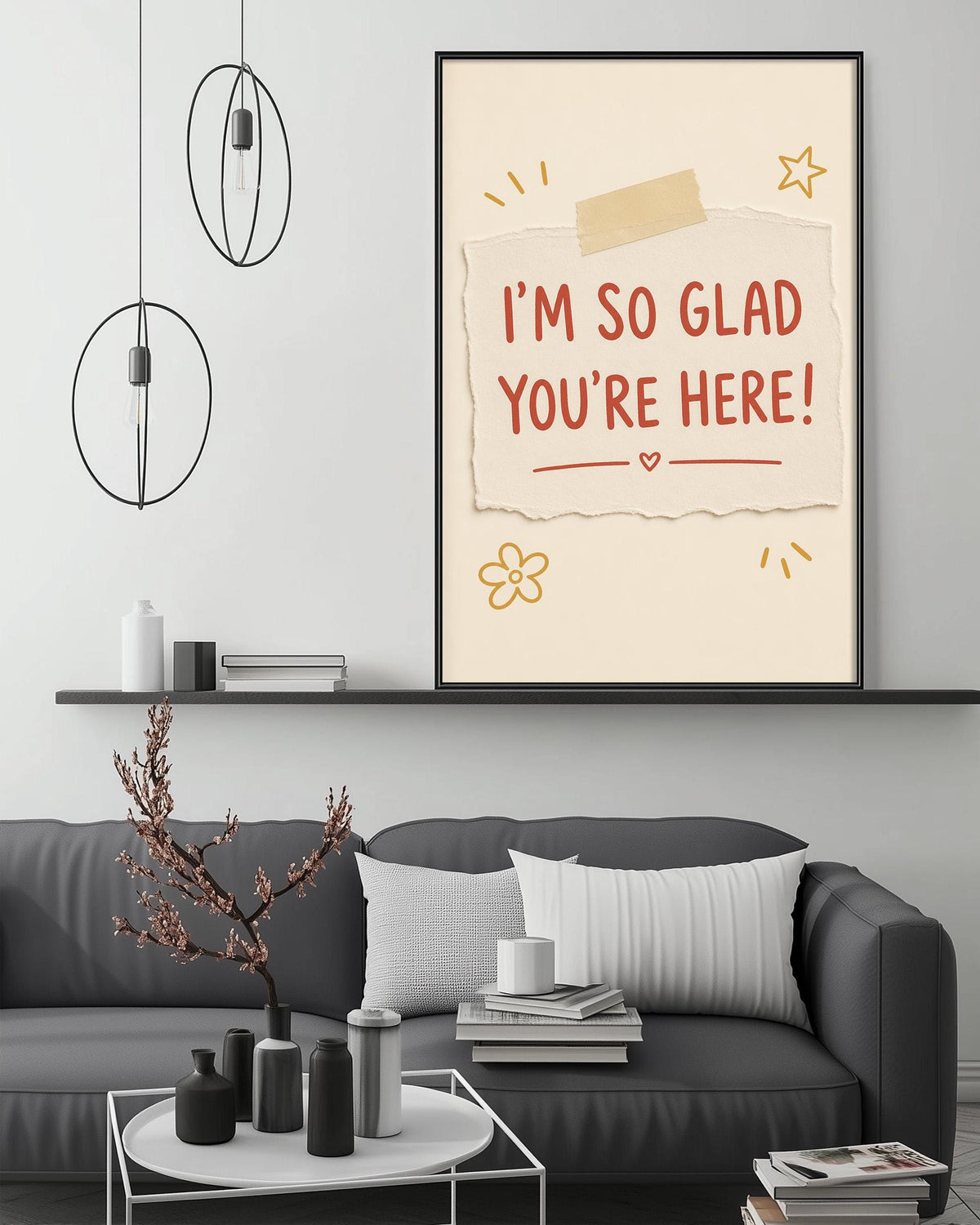 a cozy living room with a gray couch, a coffee table, and a framed poster on the wall. The poster has a message that reads "I'm so Glad You're Here!" and includes a heart and a flower.