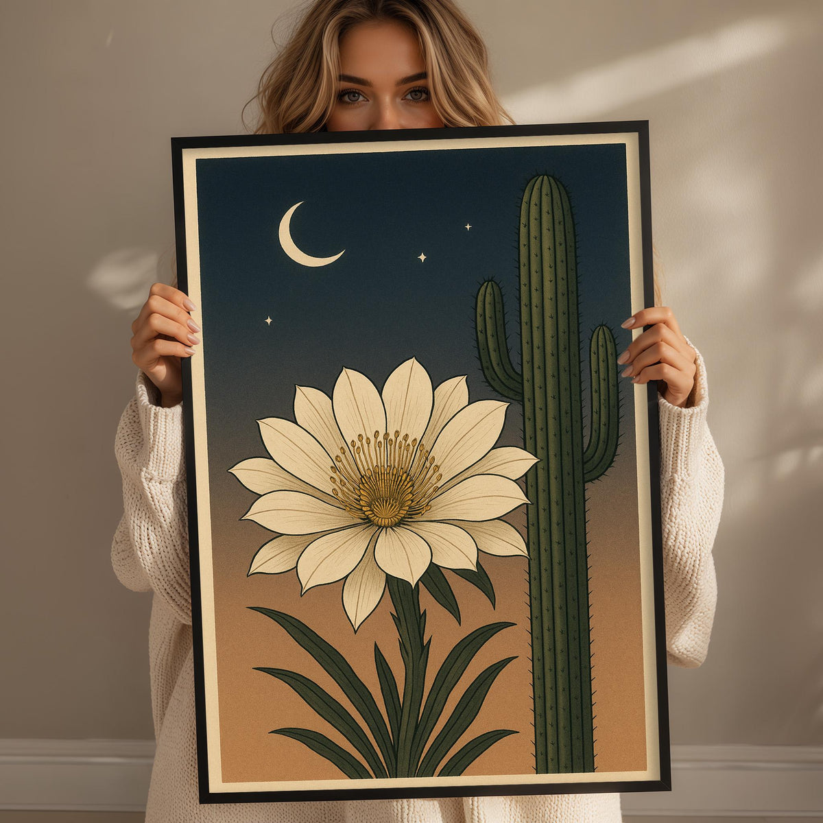 A woman holds a framed illustration of a cactus and a white flower against a night sky background.