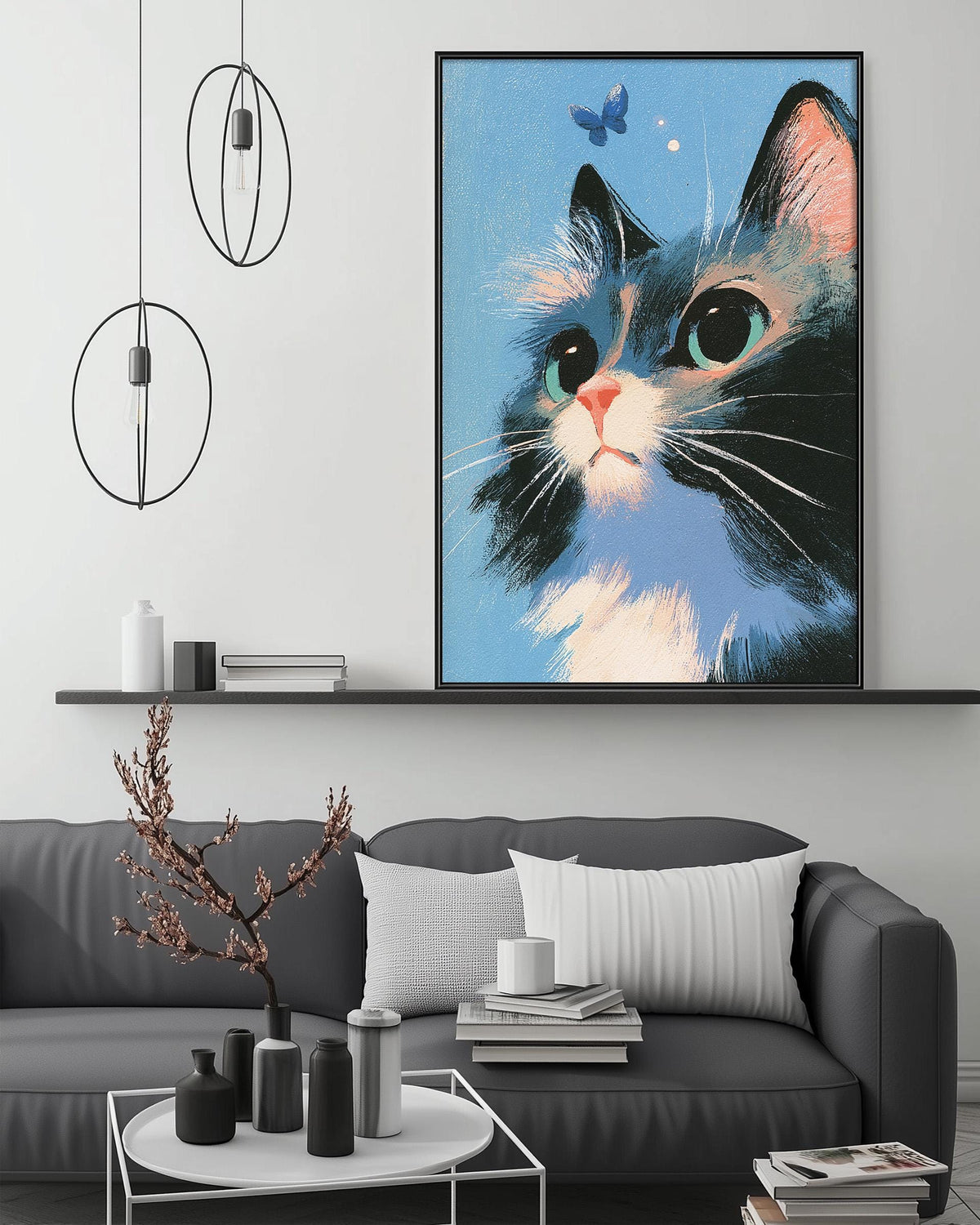 a large framed painting of a cat with a blue background and white and black accents, hanging on a wall above a gray couch with white pillows.