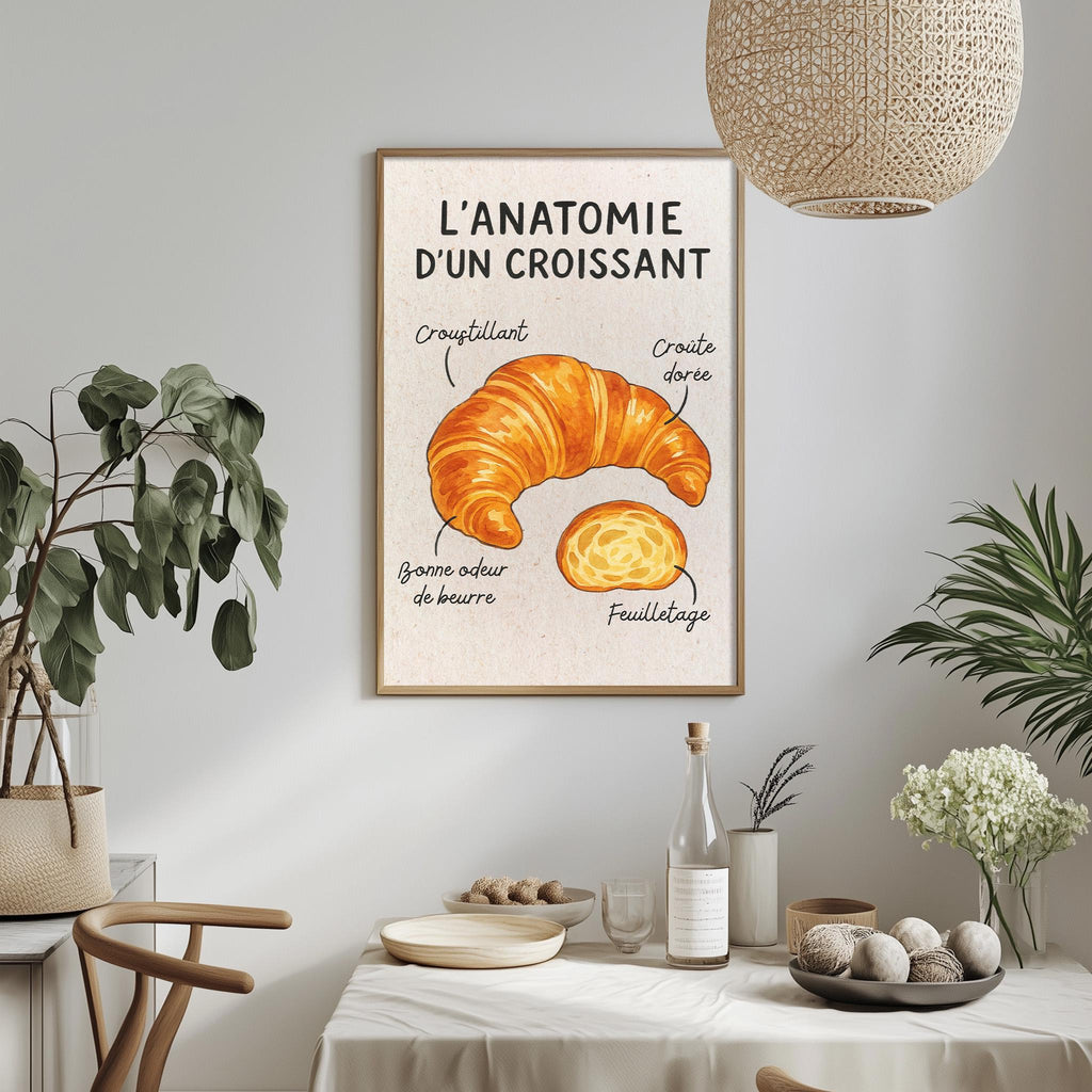 a framed poster of a croissant hanging on a wall, with a dining table and chairs in the foreground.