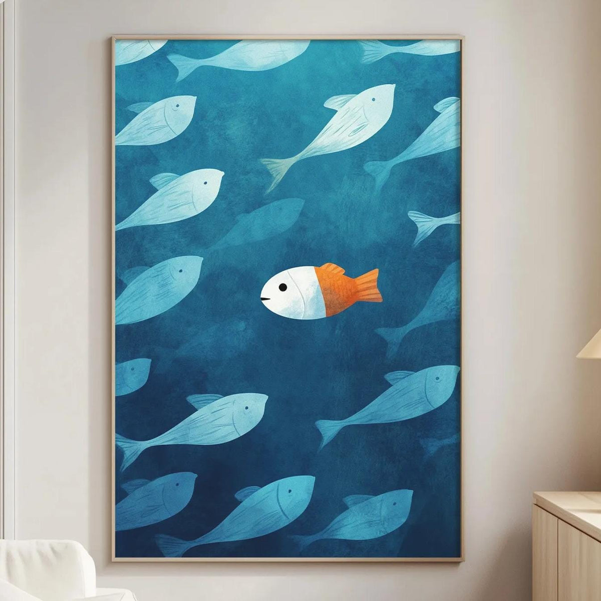 a large painting of a blue ocean scene with a single orange fish swimming among the blue fish. The painting is hung on a wall in a living room setting, with a white couch and a small table nearby.
