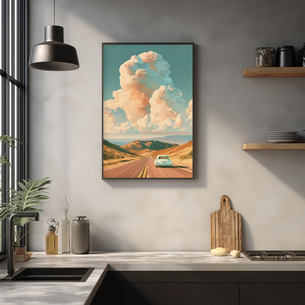 a framed painting of a road leading to a blue car, with a cloudy sky in the background, hanging on a wall above a kitchen counter.