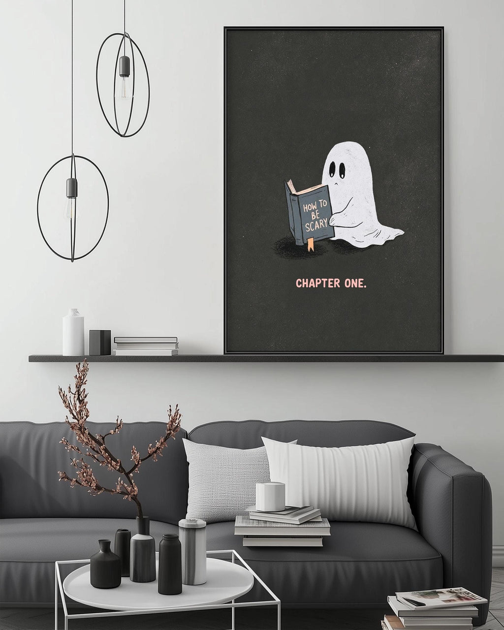 a cozy living room with a gray couch, a coffee table, and a large framed poster of a ghost reading a book. The poster has the text "How to scare someone" and "CHAPTER ONE" written on it.