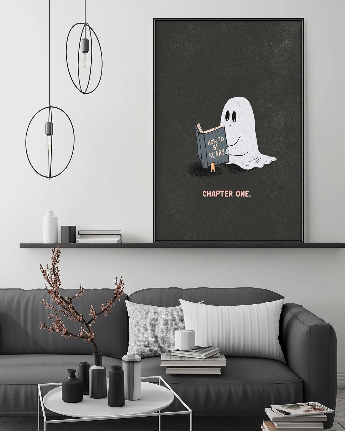 a cozy living room with a gray couch, a coffee table, and a large framed poster of a ghost reading a book. The poster has the text "How to scare someone" and "CHAPTER ONE" written on it.