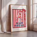 A framed poster with a red and white striped background and a glass of red berry-flavored drink, along with the text "BERRY BEACH BAR".