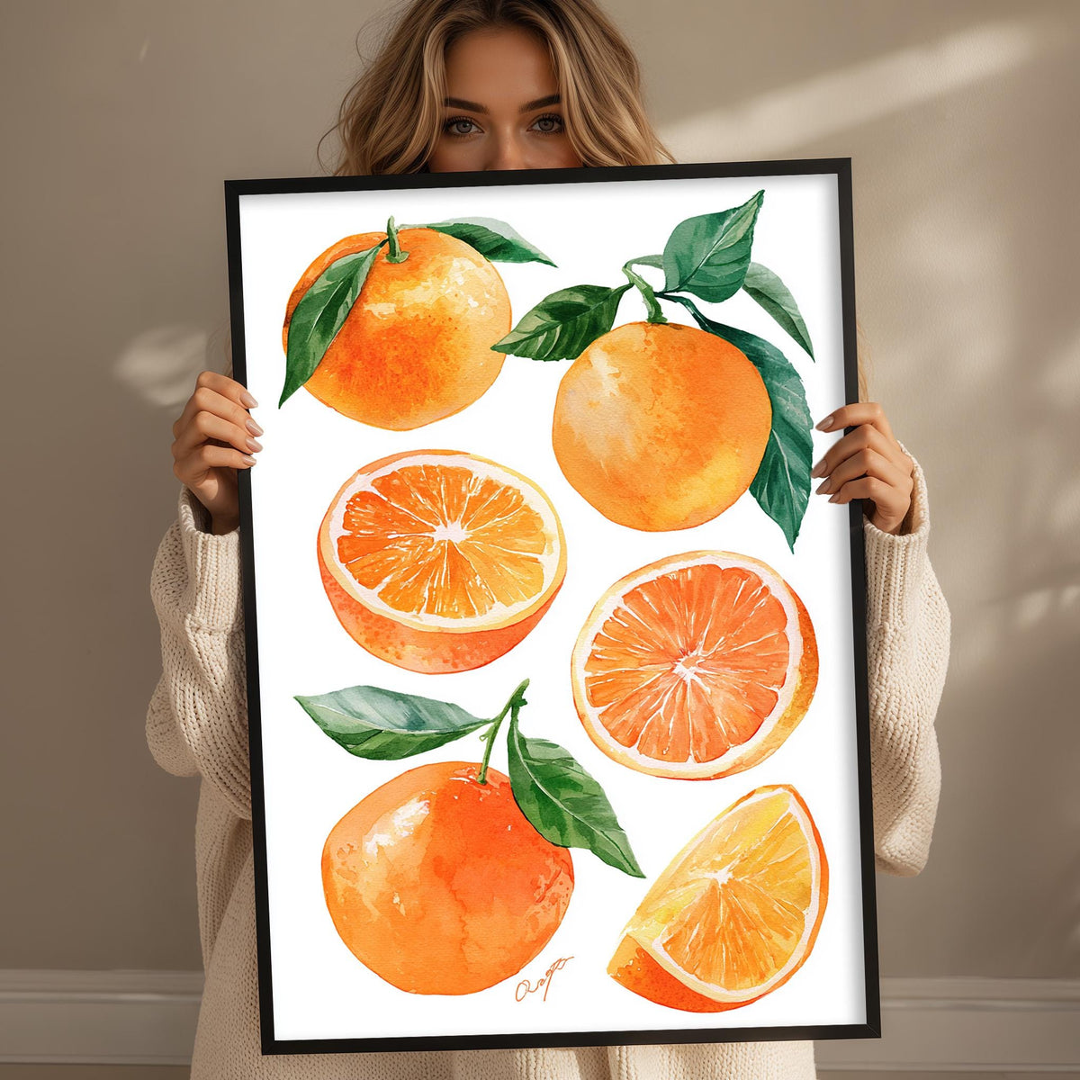 A woman holds up a framed print featuring vibrant illustrations of oranges, including whole oranges, sliced oranges, and green leaves.