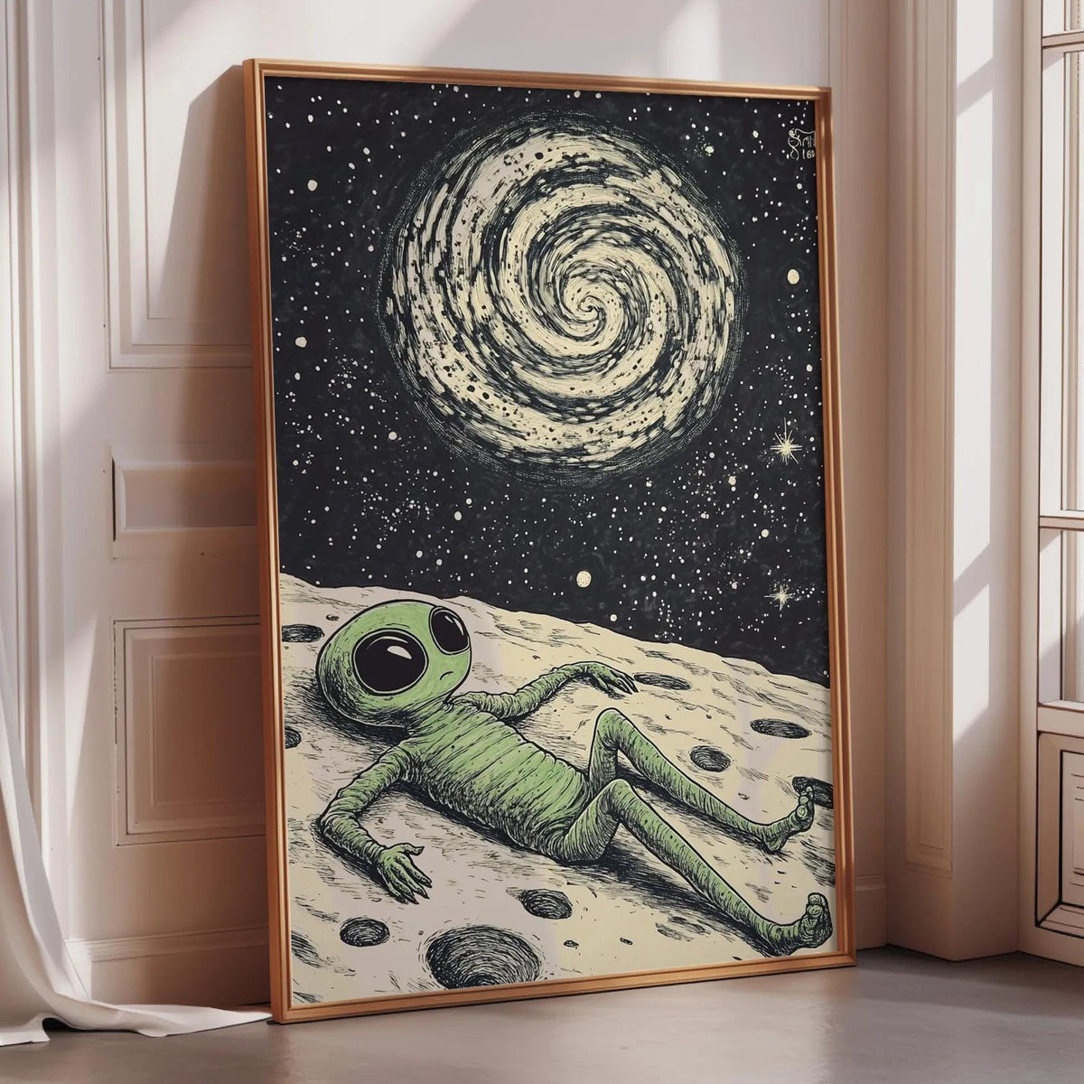 a framed illustration of an alien lying on the ground, looking up at the night sky with a spiral galaxy above.