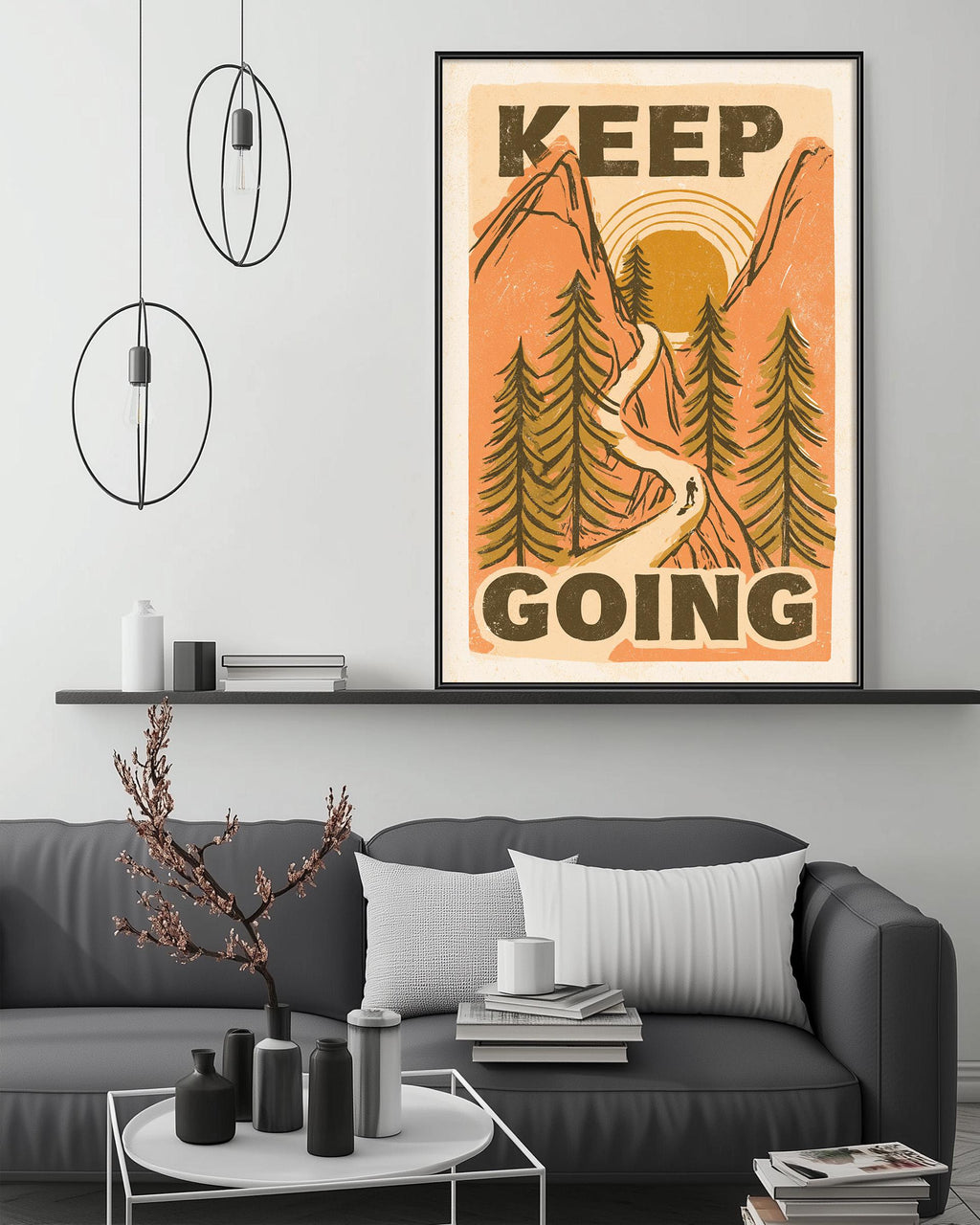 a living room with a gray couch, a coffee table, and a framed poster with a mountain landscape and the text "KEEP GOING" displayed on the wall above the couch.