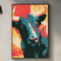 a kitchen counter with a framed painting of a bull's head hanging on the wall above it. The painting has a vibrant, colorful design with bold red, orange, and blue hues. The kitchen counter also has various items such as a cutting board, a bottle, and a vase.