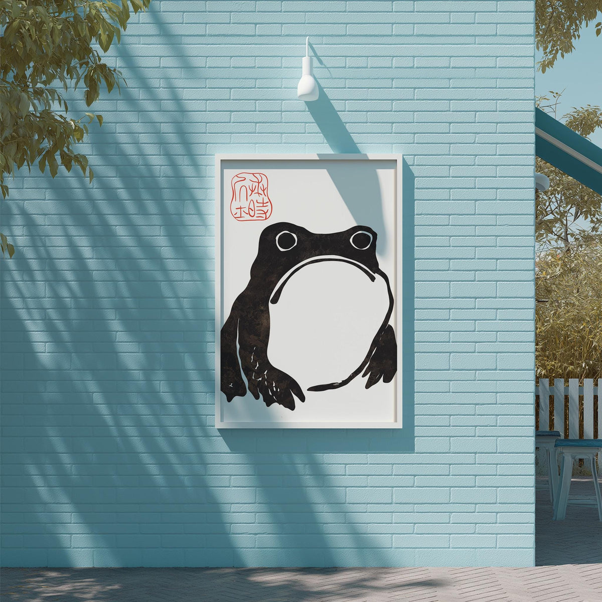 a framed artwork of a frog on a blue wall, with a white light fixture above it.