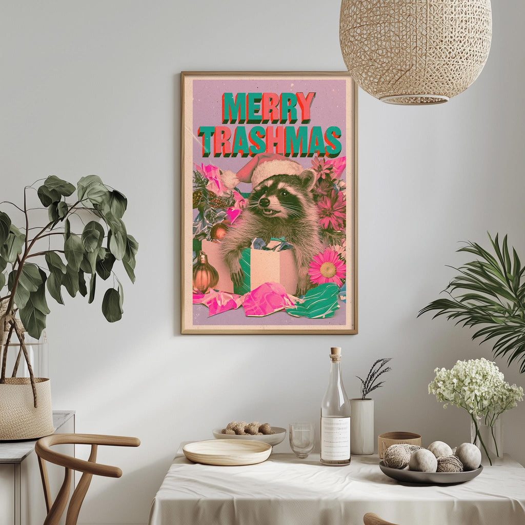 a framed poster with a raccoon wearing a Santa hat, surrounded by Christmas decorations, on a wall above a dining table with various items on it.