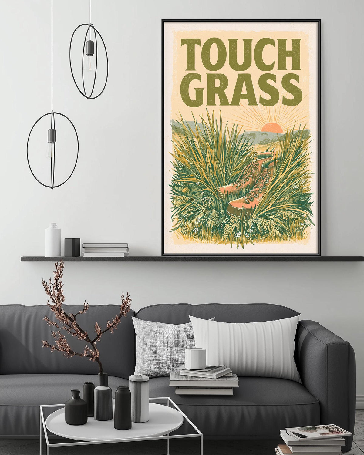a living room with a gray sofa, a coffee table, and a framed poster of a grassy landscape with a sun and a path.