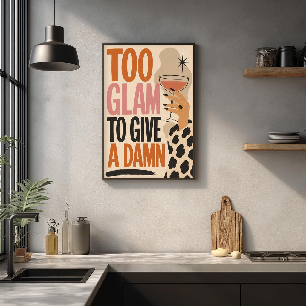 a kitchen counter with various kitchen items, such as a cutting board, a bottle, and a bowl. Above the counter, there is a framed poster with the text "Too Glam to Give a Damn" displayed on it.