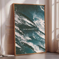 a large framed poster with a striking abstract design of swirling, teal-colored waves.